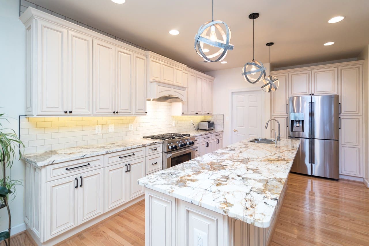 An elegant kitchen with white cabinets and marble countertops