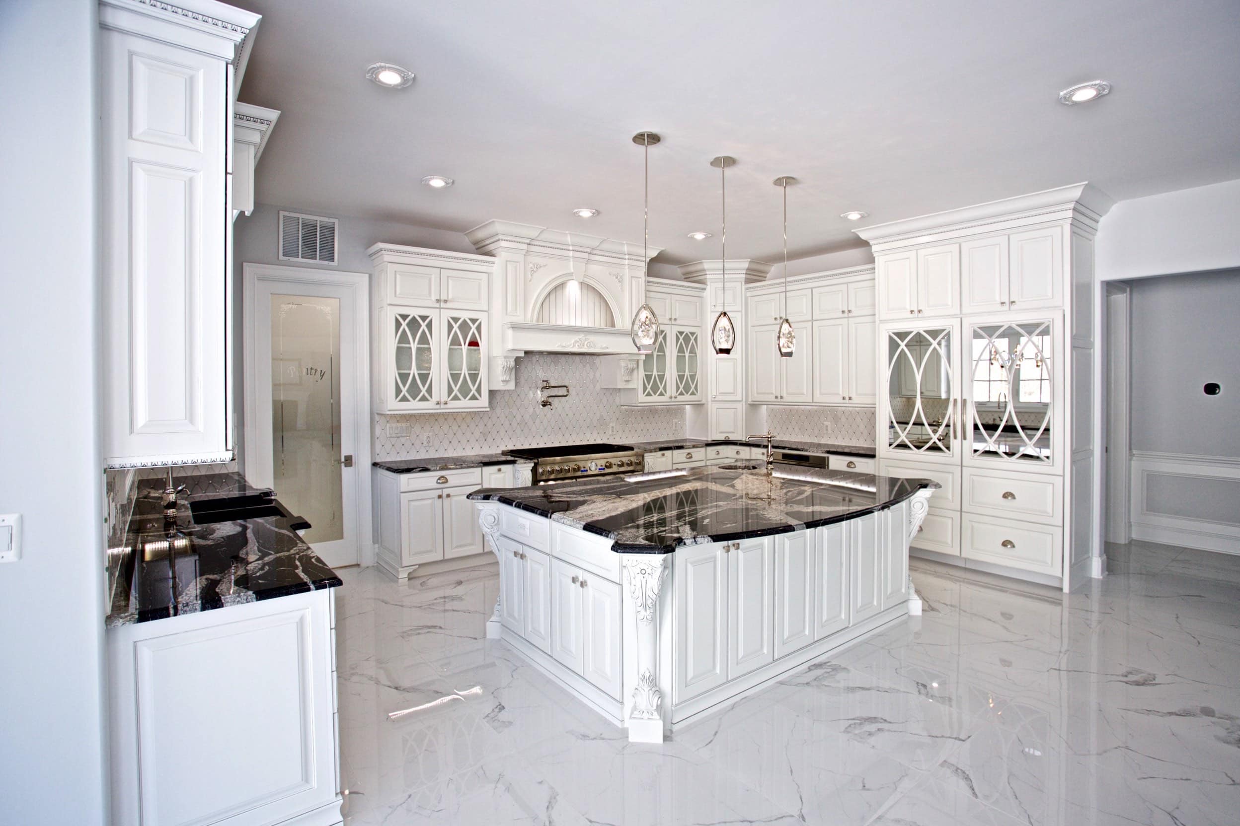 A spacious white kitchen with elegant marble countertops