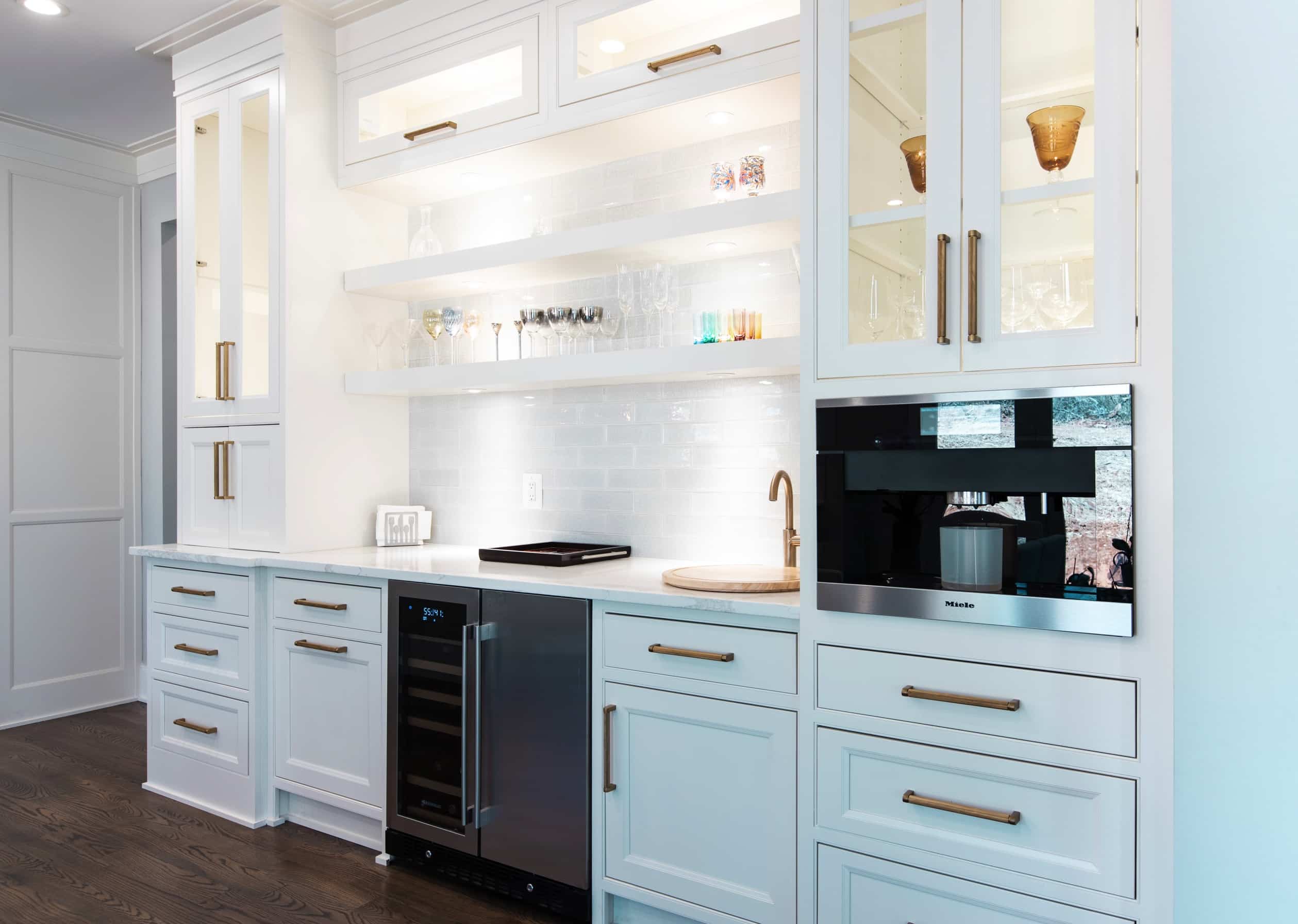 A kitchen with white cabinets and a mini refrigerator