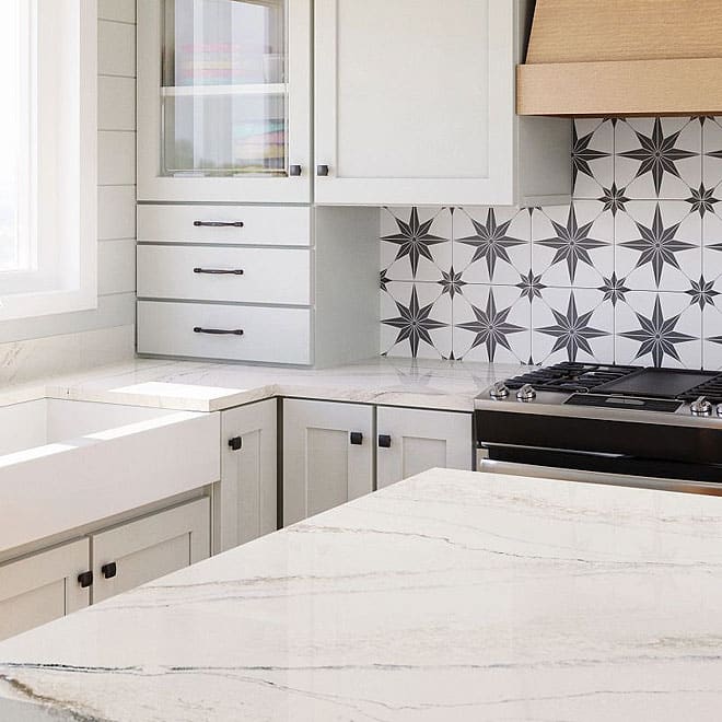 Cambria 11 Modern kitchen with marble countertops, white cabinetry, a farmhouse sink, gas stove, and a backsplash