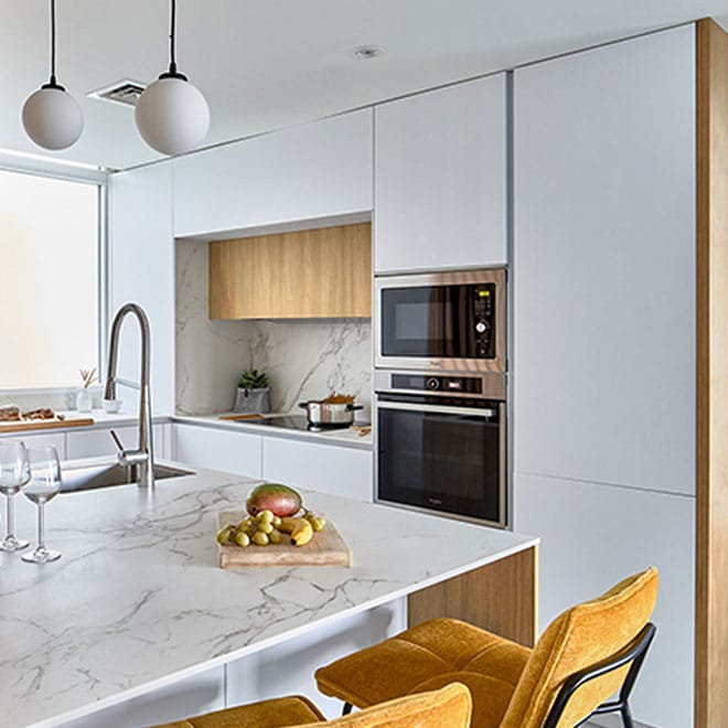 Dekton 9 A modern kitchen with marble counter tops and yellow chairs.