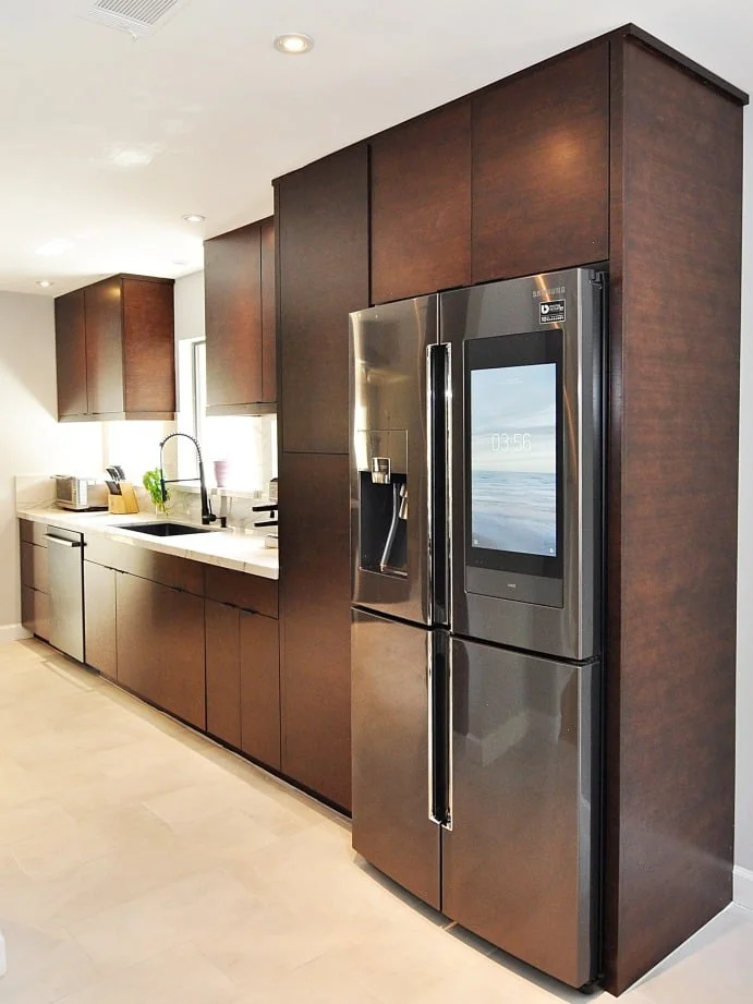 Stainless steel refrigerator and built-in microwave with brown cabinets in Houston home