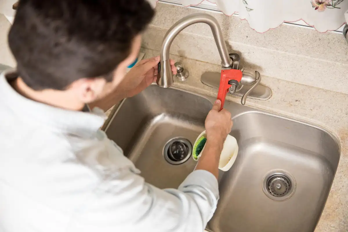 man replacing old bathroom faucet