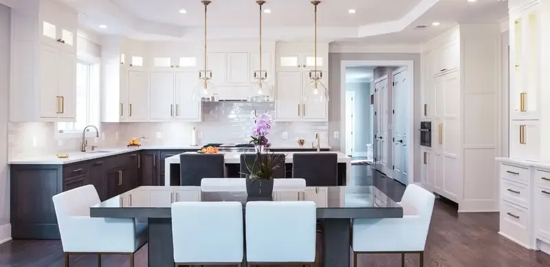 White shaker kitchen featuring a quartz waterfall island and brass globe pendants.